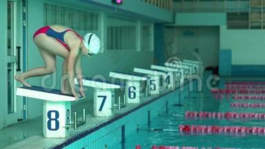 少女游泳运动员在游泳池跳水。女游泳运动员在游泳池里跳水做游泳运动。